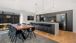 Eine moderne Küche mit einer zentralen Kochinsel, Barhocker und einem Edelstahl-Kühlschrank.