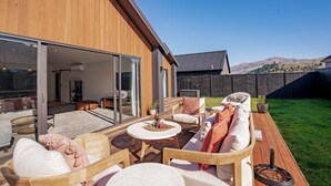 Ein modernes Haus mit Terrasse, Sitzgelegenheit im Freien und Blick auf die Berge.