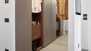 Una habitación de hotel moderna con vestidor, espejo y perchero.