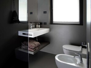 A modern bathroom with a built-in sink, a toilet, and a towel rack. - An outdoor paradise (Arco)