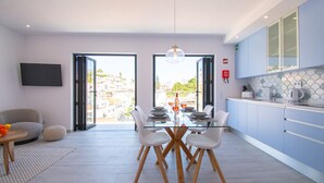 Une cuisine moderne avec un coin repas, de grandes fenêtres et un téléviseur à écran plat.