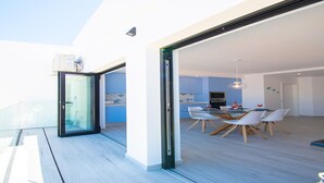 Un intérieur moderne comprenant un coin repas, une cuisine et une porte vitrée donnant sur un espace extérieur.