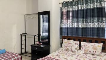A bedroom with a bed, a dresser, a mirror, and a window with curtains.
