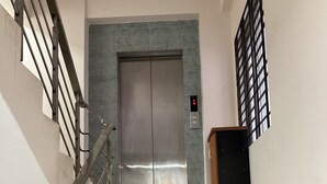 A staircase leading to an elevator with a metal railing on the left. - Appayan Guest House Baridhara (Dhaka)