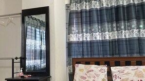 A bedroom with a bed, a nightstand, a mirror, and a window with curtains. - Appayan Guest House Baridhara (Dhaka)