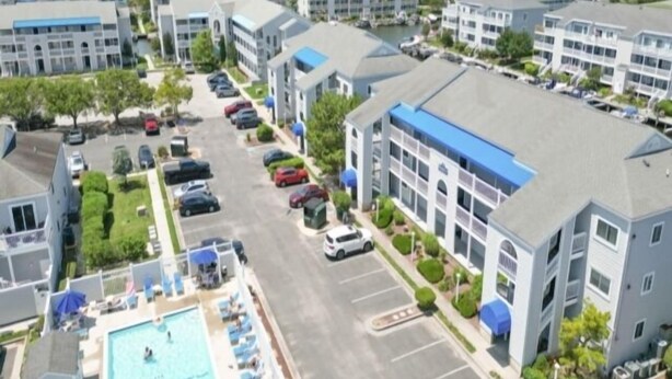 Un ensemble immobilier résidentiel comprenant une piscine, un parking et offrant une vue sur la mer.
