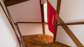 Een houten trap met metalen leuningen en een rood voorwerp aan de muur.