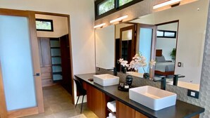 Un baño moderno con dos lavamanos, un espejo grande y un mueble de tocador de madera.