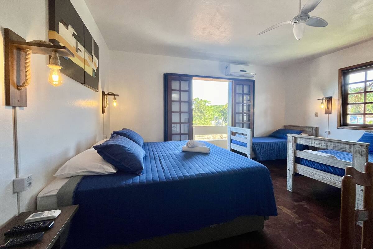 A room with two beds, a ceiling fan, and a window with a view.
