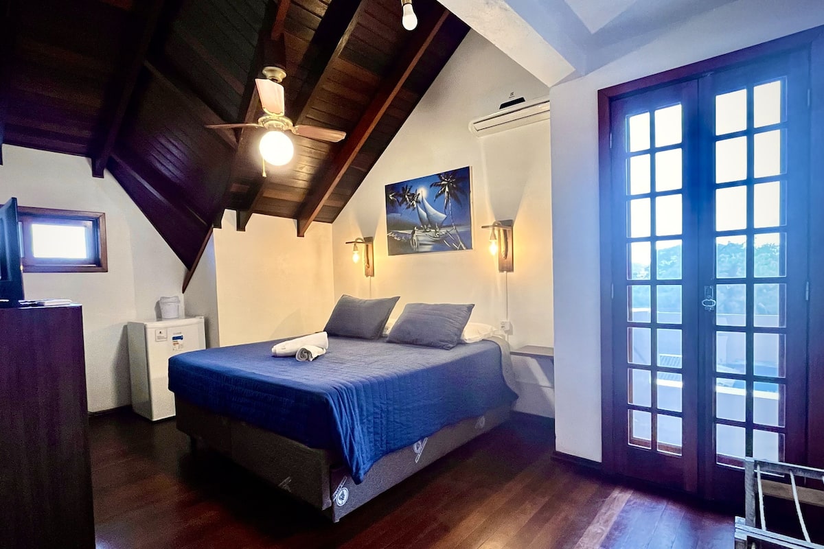 A bedroom with a bed, a ceiling fan, a painting, a window, and a door.