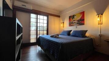 Quarto com cama, janela, ventilador de teto e luminárias fixadas na parede.