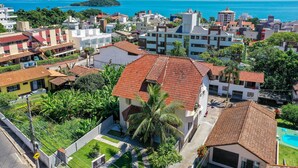 A residential area with a mix of modern and traditional architecture, featuring a prominent building with a red-tiled roof and a well-maintained garden. - Pousada Canajurê (Florianópolis)