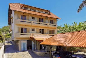 A multi-story building with a tiled roof, balconies, and a covered outdoor seating area. - Pousada Canajurê (Florianópolis)