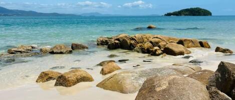 A beach with large rocks and clear water.
