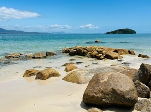 A beach with large rocks and clear water. - Pousada Canajurê (Florianópolis)
