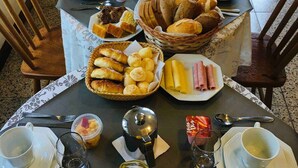 A breakfast table set with various dishes, including bread, pastries, and fruit. - Pousada Canajurê (Florianópolis)