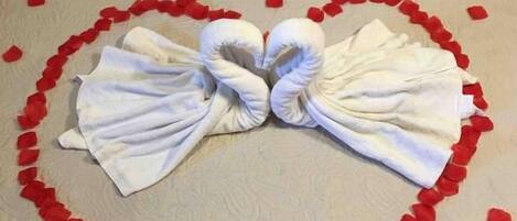 Un letto con una composizione a forma di cuore di petali di rosa e asciugamani.