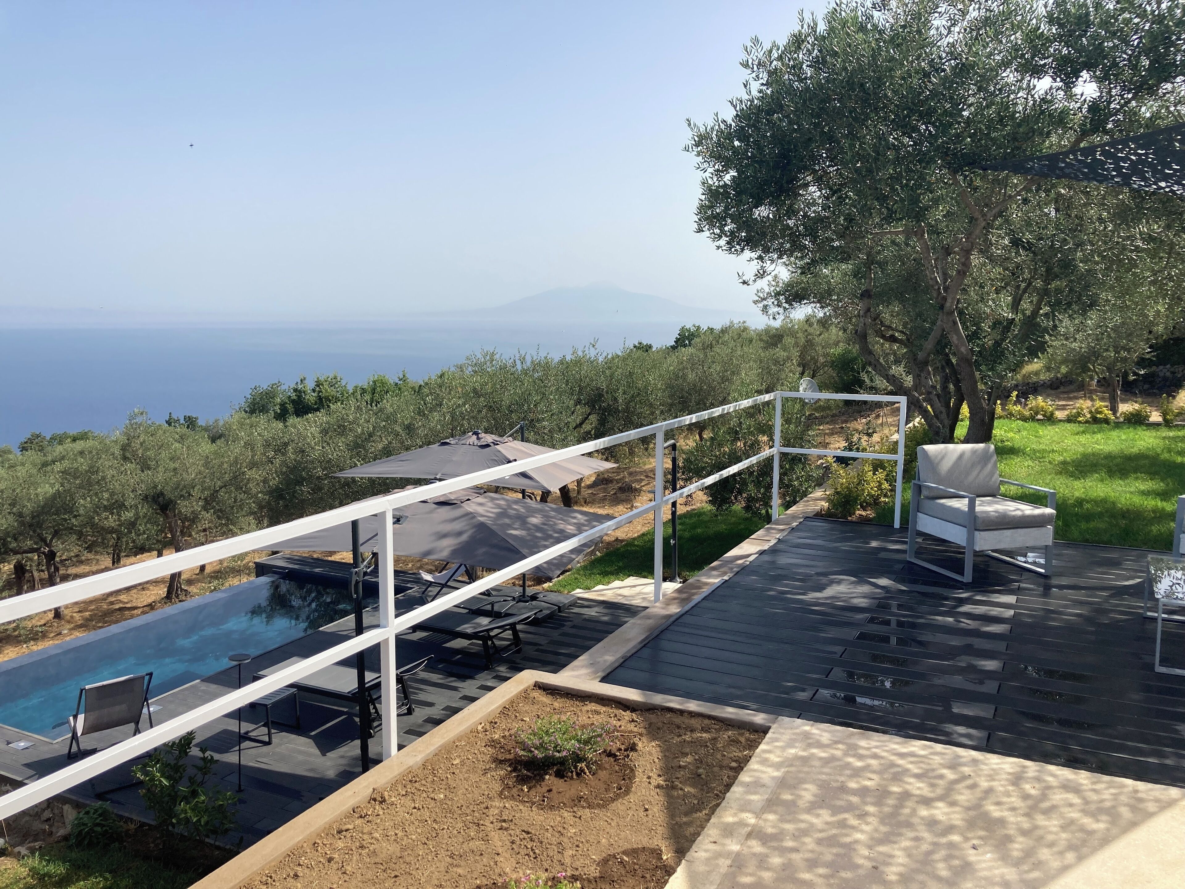 Zona de piscina con vistas al mar, mobiliario exterior y una estructura de pérgola.