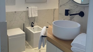 Ein modernes Badezimmer mit einem großen Waschbecken, einem Spiegel, einem Fenster und einem Handtuchhalter.