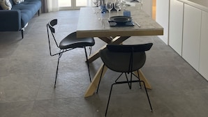 Ein moderner Essbereich mit einem Marmortisch, schwarzen Stühlen und einer Deckenleuchte.