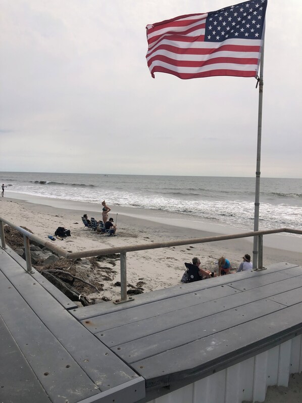 Guests can enjoy the ocean view from the beach, where a flag waves gently in the breeze.