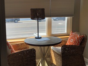 Relax in this inviting seating area with a round table and two comfortable chairs, perfect for taking in the view of the street outside.