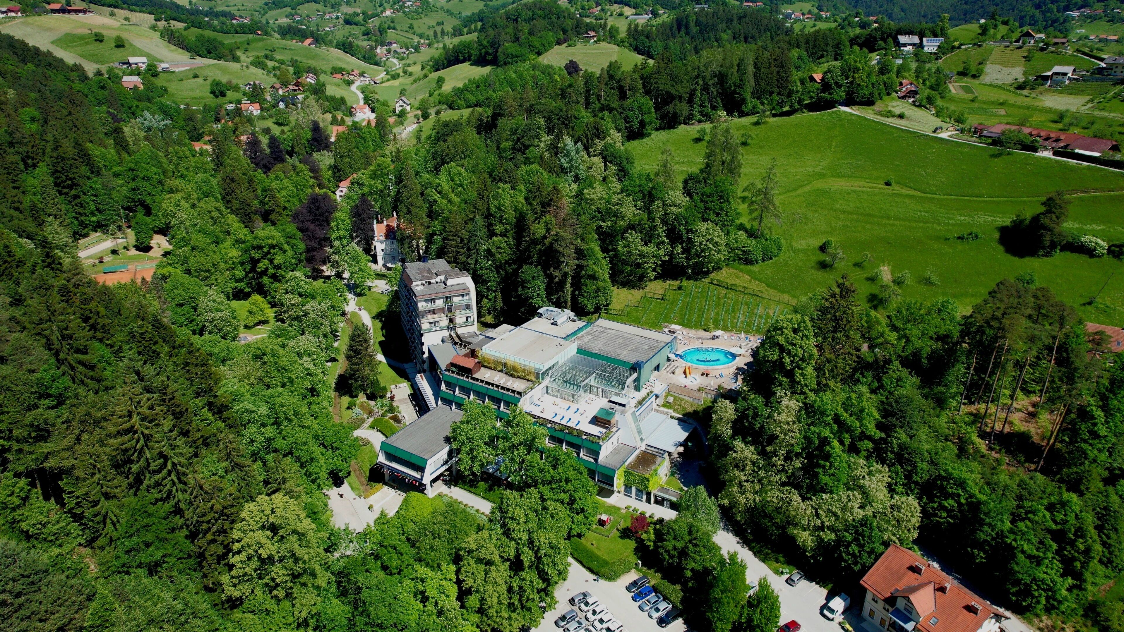Vista aérea de un hotel con piscina, rodeado de vegetación exuberante y terreno montañoso.