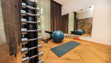 A gym with exercise equipment, a yoga mat, and a mirror on the wall.