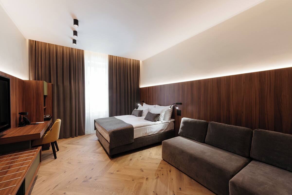 Ein modernes Hotelzimmer mit Bett, einer Couch, einem Schreibtisch und einem Fernseher.
