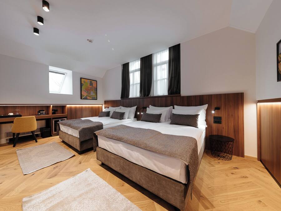 A modern hotel room with two beds, a desk, and a chair.
