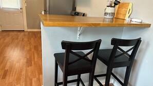 A small kitchen with a wooden countertop, two black chairs, a refrigerator, and a microwave. - Peaceful home with an amazing yard near downtown San Antonio. Pet Friendly! (San Antonio)