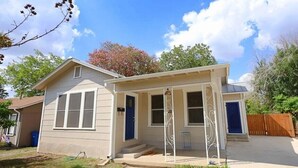 A single-story house with a front porch, a garage, and a small front yard. - Peaceful home with an amazing yard near downtown San Antonio. Pet Friendly! (San Antonio)