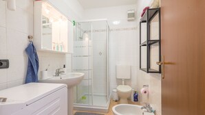 Une petite salle de bain comprenant une douche, des toilettes, un lavabo et un étendoir.