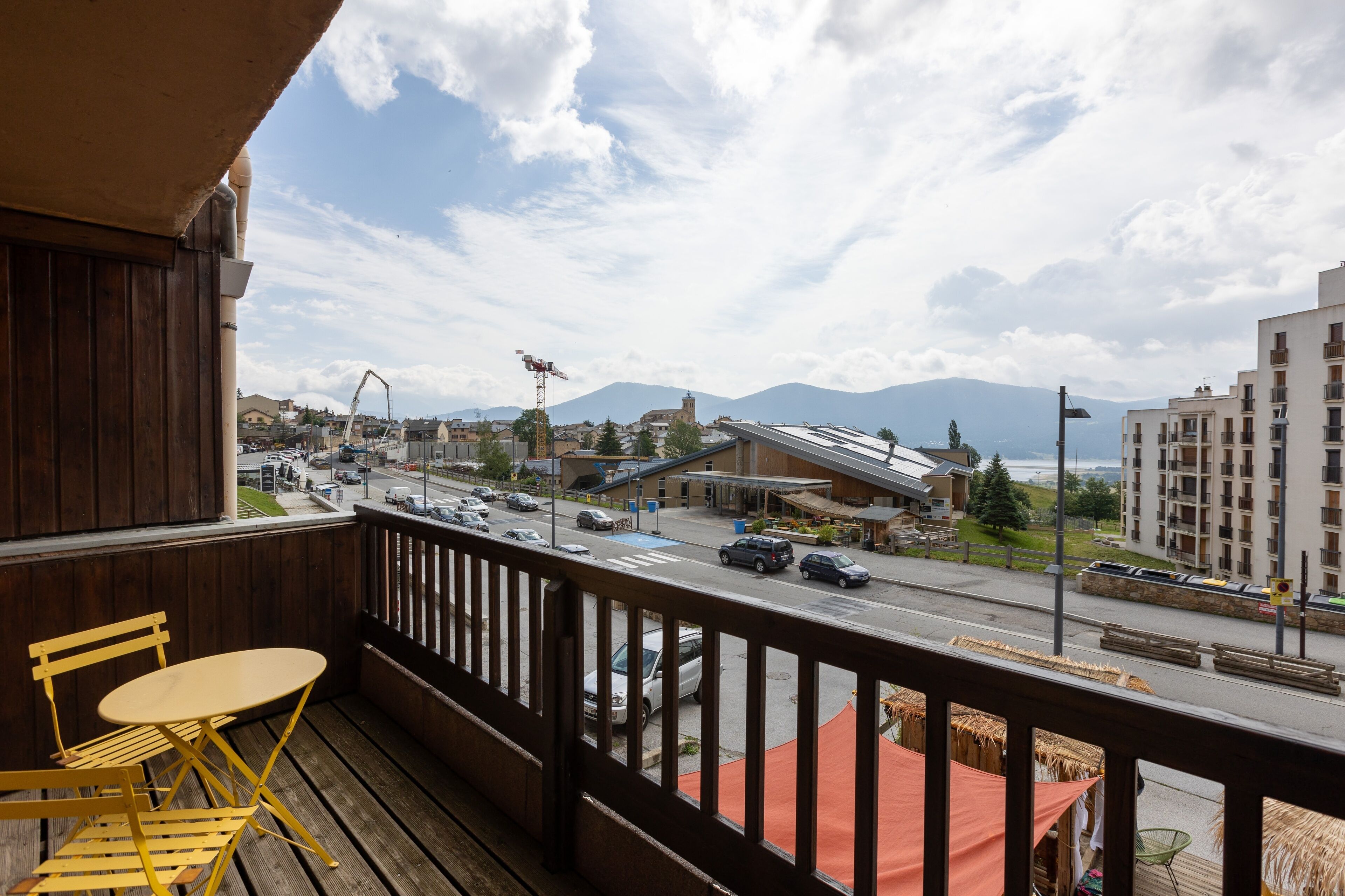 A balcony with wooden railings, a yellow folding table, and a chair.