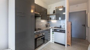 A compact kitchen with dark cabinets, a microwave, a toaster, and a coffee maker. - Zénitude - Appartement au pied des pistes (Les Angles)