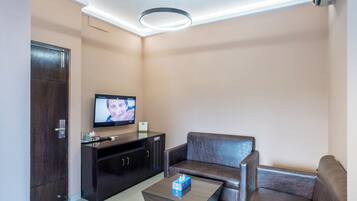 Una sala de estar moderna con un mueble bajo de madera oscura, un sofá de cuero, una mesa de centro y un televisor de pantalla plana montado en la pared.