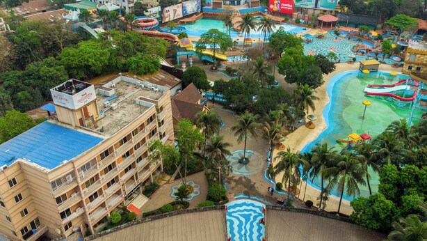 Un complexe hôtelier doté de plusieurs piscines, de toboggans aquatiques et de palmiers.