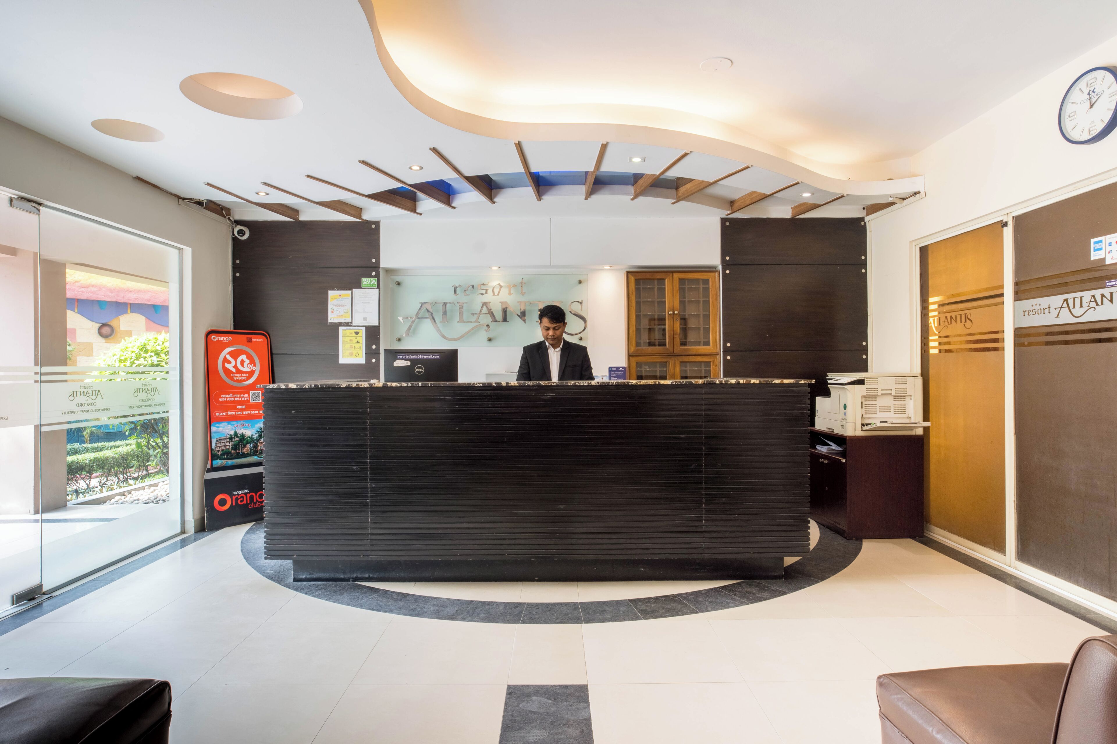 A reception desk with a modern design, a clock on the wall, and a sign for the resort.
