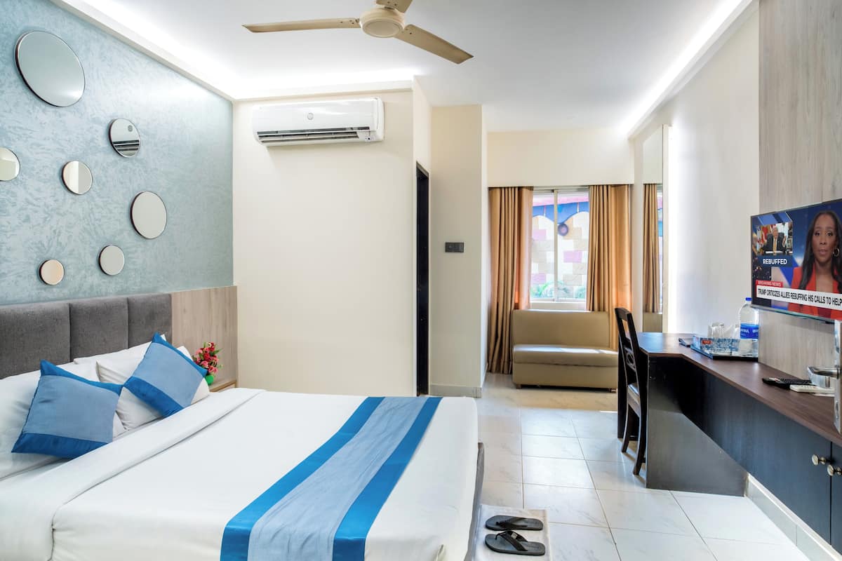 Une chambre d’hôtel équipée d’un lit, d’un bureau, d’une télévision et d’un ventilateur de plafond.