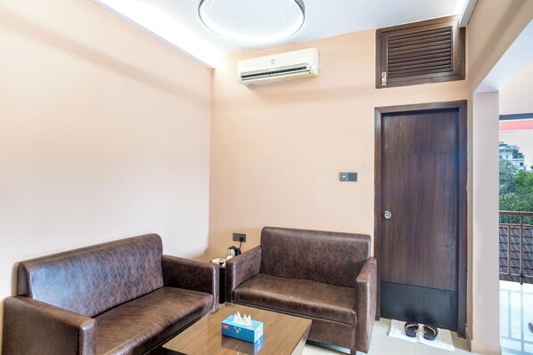 A room with two brown leather sofas, a small wooden coffee table, an air conditioning unit, a door, and a balcony with a railing. - Resort Atlantis (Savar)