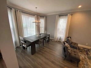 Un espace repas avec une table en bois foncé, des chaises en verre transparent et un lustre.