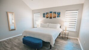 A bedroom with a large bed, a bench, a mirror, and artwork on the wall. - Spark Getaways: The Golden Lotus Spa, Sauna, EV Charging (Lubbock)