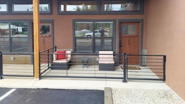 A building entrance with a covered porch, large windows, and a gated driveway.