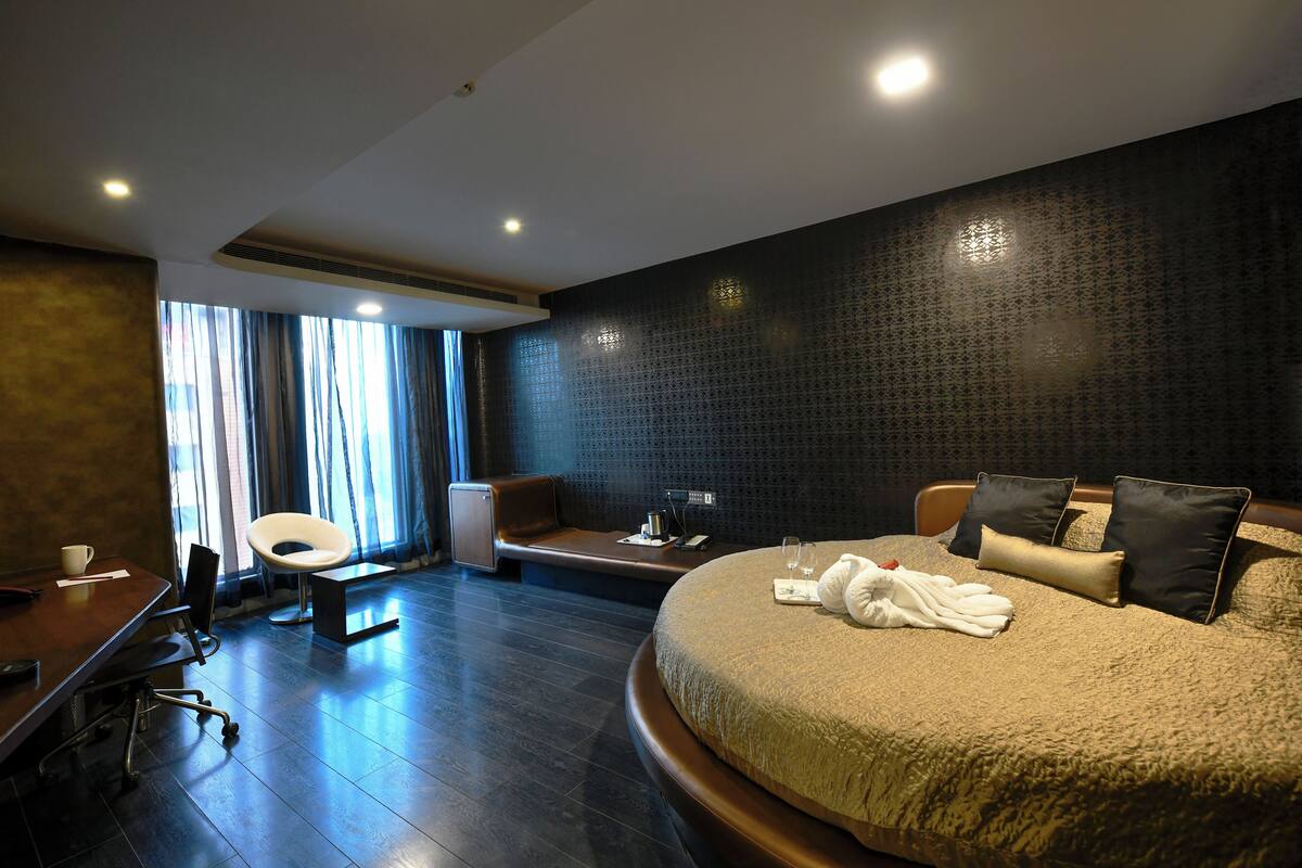 Una habitación de hotel moderna con una cama grande, un escritorio y una zona de estar.