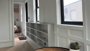 Un corridoio con pareti bianche, finestre a cornice nera e scaffalature integrate.