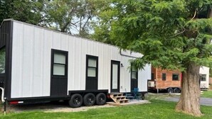 Un camper con tetto piatto, ampie finestre e un piccolo portico.