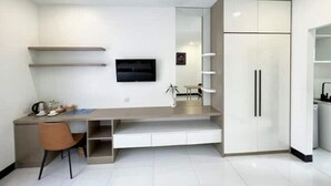 Una cocina moderna con escritorio integrado, refrigerador y televisor montado en la pared.