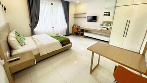 Habitación de hotel con cama, escritorio, silla, televisor y armario.