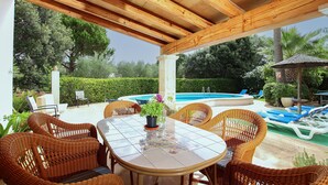 An outdoor patio with wicker furniture, a tiled table, and a pool in the background. - FONT CAMPO (MAR). Lovely villa in Pollensa with heated pool (Pollensa)