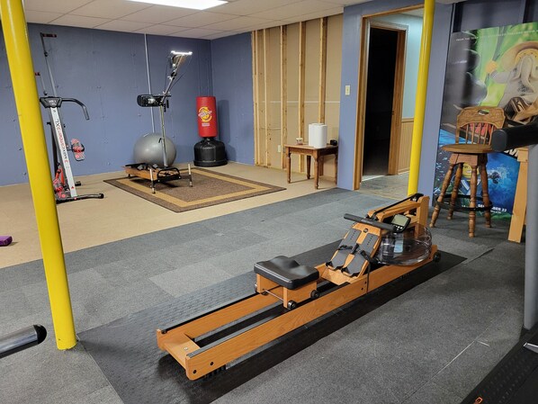A gym with exercise equipment, a punching bag, and a wooden chair.